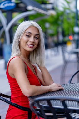 Canlı genç bir kadın, bahar sıcağının tadını çıkararak hareketli şehir sokaklarında yürüyor. Etrafında yüksek binalar yükseliyor ve onun ışıl ışıl neşesi şehir hayatının enerjisini yansıtıyor..