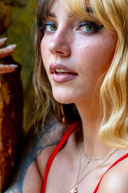 Işıl ışıl, iki tonlu saçlı, koyu kahverengi ve karamel karışımlı genç bir Meksikalı Amerikalı kadın sıcak bir şekilde gülümsüyor. Parkta güneşli bir yaz gününün tadını çıkarıyor, yemyeşil ve canlı çiçeklerle çevrili..