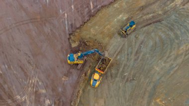 An aerial view of a bustling construction site shows bulldozers, trucks, and grading equipment shaping the land, with dirt roads, cleared areas, and scattered materials clipart