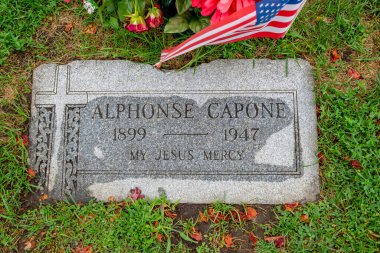 Alphonse Capone, the infamous Chicago mobster, rests in Mt. Carmel Cemetery, Hillside, Illinois, in a modest family plot marked by a simple headstone amid ornate markers of other notables. clipart