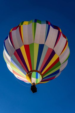 Vibrant air balloons of all shapes and colors soar into the clear blue sky, filling the air with excitement during a crisp autumn balloon fest. The scene is breathtaking against the season's beauty. clipart