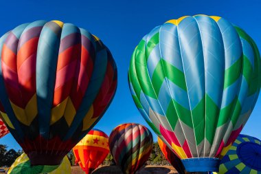 Vibrant air balloons of all shapes and colors soar into the clear blue sky, filling the air with excitement during a crisp autumn balloon fest. The scene is breathtaking against the season's beauty. clipart