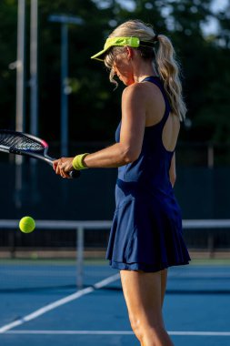 Enerjiyle parlayan genç ve güzel bir atlet, parlak yaz güneşi altında yoğun bir tenis turu atıyor. Onun hızlı hareketleri ve odaklanmış bakışları zarafeti, gücü ve oyuna olan tutkusunu simgeliyor..