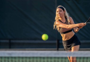 Enerjiyle parlayan genç ve güzel bir atlet, parlak yaz güneşi altında yoğun bir tenis turu atıyor. Onun hızlı hareketleri ve odaklanmış bakışları zarafeti, gücü ve oyuna olan tutkusunu simgeliyor..