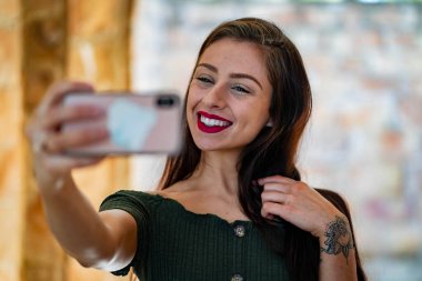 Çekici genç bir esmer, dalgalı beyaz bir bahar elbisesi içinde, saçları dalgalar halinde dalgalanırken dışarıda poz veriyor. Gülümsüyor, uzun ve sert bir kışın ardından baharın yumuşak sıcağında güneşleniyor..