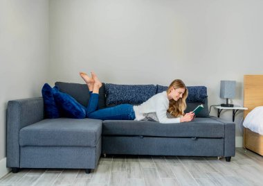 Çekici sarışın bir model şık, güneşli evinde rahatlar ve kitap okur. Onun sakin sabahı, şık iş gününe geçmeden önce tonu belirler..