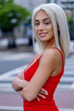 Canlı genç bir kadın, bahar sıcağının tadını çıkararak hareketli şehir sokaklarında yürüyor. Etrafında yüksek binalar yükseliyor ve onun ışıl ışıl neşesi şehir hayatının enerjisini yansıtıyor..