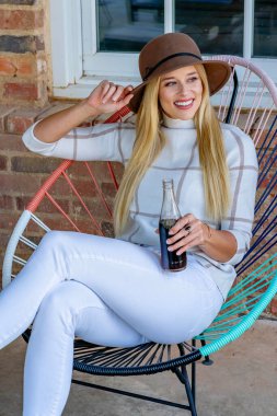 Şık giyinmiş, göz kamaştırıcı genç bir sarışın açık hava alışveriş merkezinde gazoz içiyor. Güneş onu sıcağa boğuyor. O, canlı ve açık havada esen enerjiyi ve rahatlatıcı esintiyi içine çekerken..