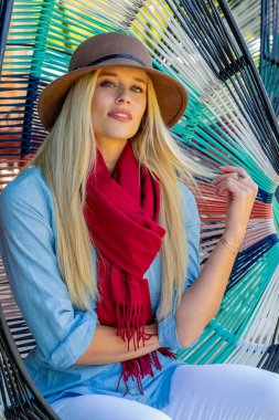 Sarışın, güzel bir kadın yerel bir alışveriş merkezinde geziniyor, açık havayı seyrediyor. Rahat bir gülümseme ile, canlı ortamın canlı atmosferinin ve sıcak güneşin tadını çıkarıyor..