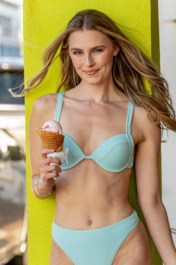 Muhteşem bir kadın kumlu bir plajda uzanmış, bikinisi altın tenine vurgu yapıyor. Dondurma külahını seviyor, güneşin sıcaklığı onu kucaklarken, dalgalar kıyıya hafifçe fısıldıyor..