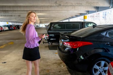 Güzel sarışın bir kadın, iş kıyafeti giymiş, loş bir otoparkta arabasına doğru gidiyor. Yorgun ama sakin bir şekilde uzun ve verimli bir iş gününden sonra kapıyı açar..