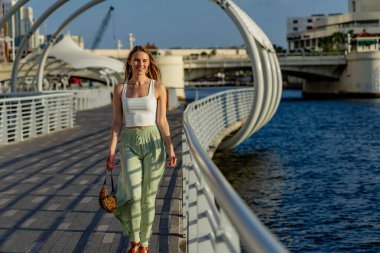 Çekici genç bir sarışın model şehir merkezinde poz veriyor. Şık yaz kıyafeti parlak mavi gökyüzüne tamamen zıt düşüyor. Kendine güveni tam, sıcaklığı ve zahmetsizliği yayıyor..