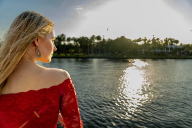 Çekici genç bir sarışın model şehir merkezinde poz veriyor. Şık yaz kıyafeti parlak mavi gökyüzüne tamamen zıt düşüyor. Kendine güveni tam, sıcaklığı ve zahmetsizliği yayıyor..