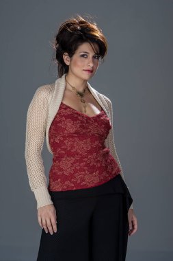 Çekici esmer saçlı bir model şık bir stüdyoda zarif bir poz veriyor. Yumuşak ışıklandırma onun özelliklerini güçlendirir, nazik gölgeler bırakır, bu arada minimalist bir arka plan onun duruşu ve güzelliğine odaklanır..