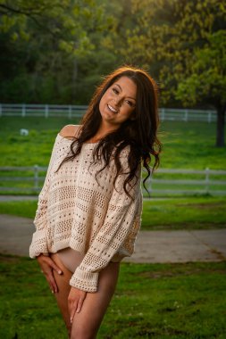 Çekici esmer, narin iç çamaşırlı güneyli kadın ılık bahar esintisinin tadını çıkarıyor, dalgalı saçları yavaşça akıyor. Kameraya özgüvenli bir poz veriyor, zarafet ve doğal güzellik yayıyor..