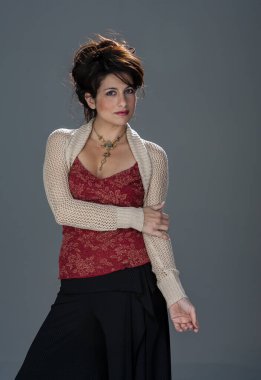 Çekici esmer saçlı bir model şık bir stüdyoda zarif bir poz veriyor. Yumuşak ışıklandırma onun özelliklerini güçlendirir, nazik gölgeler bırakır, bu arada minimalist bir arka plan onun duruşu ve güzelliğine odaklanır..