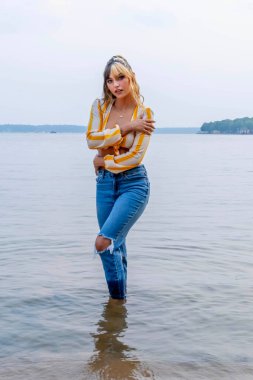 Işıl ışıl, koyu kahverengi ve karamel renkli iki tonlu saçları olan Meksikalı genç bir Amerikalı kadın sıcak bir şekilde gülümsüyor. Berrak bir göl kenarında güneşli bir yaz gününün tadını çıkarıyor. Etrafı yemyeşil ve ışıldayan suyla çevrili..