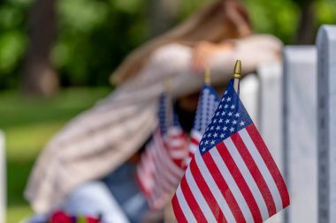 Genç bir gelin, bir askeri mezarlıkta diz çöktü. Mezarlar arasında tek sıra halinde. Tutuşan çiçekler ve bir mezar taşı, gözyaşları yüzünü seriyor sevilen bir aile üyesinin yasını tutarken derin, sessiz bir kederle..