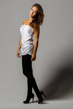 Muhteşem bir esmer model minimalist stüdyo ortamında çarpıcı bir poz veriyor. Onun zarafeti ve güzelliği sahnenin basitliği ve odağı ile gelişir..