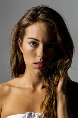 Muhteşem bir esmer model minimalist stüdyo ortamında çarpıcı bir poz veriyor. Onun zarafeti ve güzelliği sahnenin basitliği ve odağı ile gelişir..