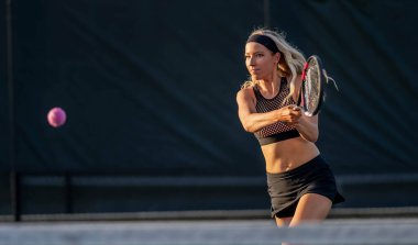 Enerjiyle parlayan genç ve güzel bir atlet, parlak yaz güneşi altında yoğun bir tenis turu atıyor. Onun hızlı hareketleri ve odaklanmış bakışları zarafeti, gücü ve oyuna olan tutkusunu simgeliyor..