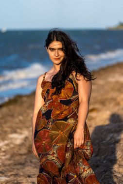 Çarpıcı esmer bir kadın, Meksika tatilinde neşeli pozlar veriyor. Güzelliği, sıcak güneş ve nefes kesici manzarayla gelişiyor. Kaygısız bir ruh yayıyor, neşeli bayram havasını kucaklıyor..