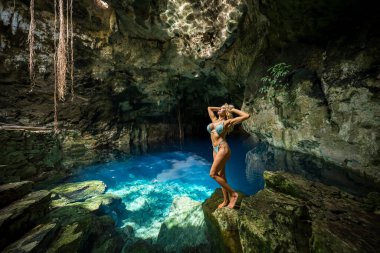 Cuzama, Yucatan, Meksika 'da, büyüleyici bir model, bir mezarlığın mavi ve yeşil sularının canlı renklerinde eğlenerek doğal güzelliğin resimsel bir manzarasını yaratıyor..