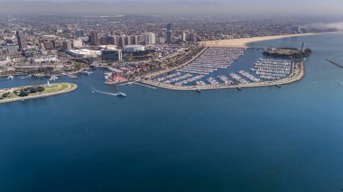 Long Beach 'in havadan görünüşü yoğun bir limanı, ikonik Kraliçe Mary' si, manzaralı deniz manzarası ve genişleyen kentsel manzarası olan canlı bir kıyı şehrini gözler önüne seriyor..