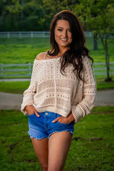 Güzel, esmer, güneyli bir kadın kameraya şık bir kesim kot pantolon ve rahat bir kazakla poz veriyor. İlkbahar gibi bir günün güzelliğinin tadını çıkarırken aynı zamanda cazibesini de yansıtıyor..