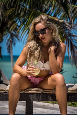 Çekici sarışın bir model, sakin bir Meksika plajında güven içinde poz veriyor. Güzelliği altın kum, nazik dalgalar ve nefes kesen doğal zarafetin sergilenen sıcak tropikal esintisiyle uyum içinde..