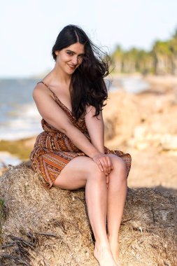 Çarpıcı esmer bir kadın, Meksika tatilinde neşeli pozlar veriyor. Güzelliği, sıcak güneş ve nefes kesici manzarayla gelişiyor. Kaygısız bir ruh yayıyor, neşeli bayram havasını kucaklıyor..