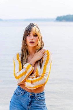 Koyu kahverengi ve karamel rengi saçlarıyla ışıl ışıl genç bir Meksikalı Amerikalı kadın. Üç tonlu saçı sıcacık gülümsüyor. Berrak bir göl kenarında güneşli bir yaz gününün tadını çıkarıyor. Etrafı yemyeşil ve ışıldayan suyla çevrili..