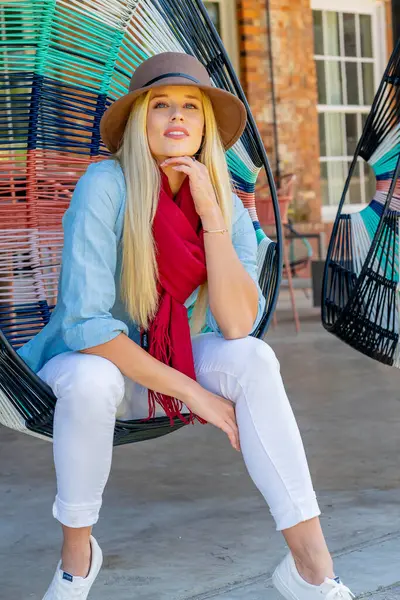 Sarışın, güzel bir kadın yerel bir alışveriş merkezinde geziniyor, açık havayı seyrediyor. Rahat bir gülümseme ile, canlı ortamın canlı atmosferinin ve sıcak güneşin tadını çıkarıyor..