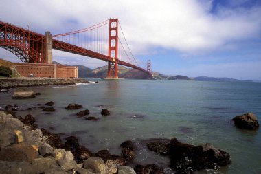 Golden Gate Köprüsü, San Francisco, Kaliforniya 'daki Pasifik Okyanusu üzerinde muazzam bir şekilde uzanır. İkonik kırmızı kuleleri mavi sularla ve gökyüzüyle çok güzel zıtlaşır..