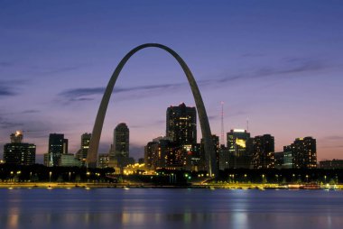 St. Louis Kemeri alacakaranlıkta şehrin siluetine karşı parlarken Mississippi Nehri ön planda sakince akıyor, sönen ışıkta parıldayan yumuşak, sessiz yansımalar yapıyor..
