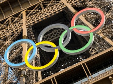 Paris 'teki Eyfel Kulesi, Olimpiyat yüzükleriyle süslenmiş, 2024 Yaz Olimpiyatları için göz alıcı bir süs olarak parlıyor, ikonik gökyüzüne karşı oyunların ruhunu ve birliği simgeliyor..
