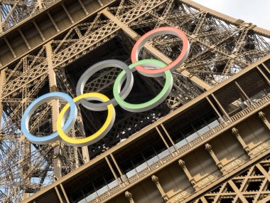 Paris 'teki Eyfel Kulesi, Olimpiyat yüzükleriyle süslenmiş, 2024 Yaz Olimpiyatları için göz alıcı bir süs olarak parlıyor, ikonik gökyüzüne karşı oyunların ruhunu ve birliği simgeliyor..