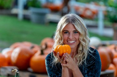 Çekici sarışın bir model canlı bir balkabağı tarlasında poz veriyor, şık bir sonbahar elbisesi giyiyor ve Cadılar Bayramı cazibesine sahip. Sıcacık turuncu renkler ve şenlikli mevsimsel titreşimlerle parlıyor..