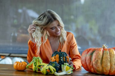 Çekici sarışın bir model canlı bir balkabağı tarlasında poz veriyor, şık bir sonbahar elbisesi giyiyor ve Cadılar Bayramı cazibesine sahip. Sıcacık turuncu renkler ve şenlikli mevsimsel titreşimlerle parlıyor..