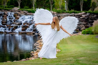 Saf beyaz giyinmiş, narin melek kanatlarıyla süslenmiş çekici genç bir sarışın zarif bir duruş sergiliyor. Onun dingin ifadesi ve akışkan elbisesi ruhani bir varlığı çağrıştırıyor, somutlaştıran melek güzelliğini..