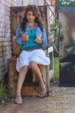 Çarpıcı genç bir melez ırk modeli, şehir ortamında kendine güvenen bir poz veriyor. Güneş ışığı, duvarların, sokak sanatının ve şehir enerjisinin arka planına vurgu yapıyor..