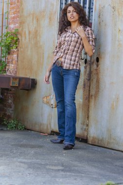 Çarpıcı genç bir melez ırk modeli, şehir ortamında kendine güvenen bir poz veriyor. Güneş ışığı, duvarların, sokak sanatının ve şehir enerjisinin arka planına vurgu yapıyor..