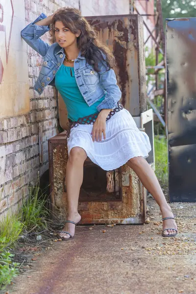 Çarpıcı genç bir melez ırk modeli, şehir ortamında kendine güvenen bir poz veriyor. Güneş ışığı, duvarların, sokak sanatının ve şehir enerjisinin arka planına vurgu yapıyor..