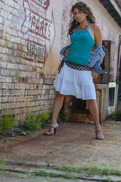 Çarpıcı genç bir melez ırk modeli, şehir ortamında kendine güvenen bir poz veriyor. Güneş ışığı, duvarların, sokak sanatının ve şehir enerjisinin arka planına vurgu yapıyor..