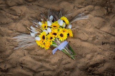 Mükemmel bir yaz gününün sıcaklığı altında, kumlu sahilde, canlı bir buket çiçek dinleniyor..