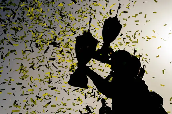 Yarışı kazananların siluetleri zafer şeridinde zafer kazanmış, konfeti yağarken ganimetler yükselmiş, yorucu bir motor sporu savaşının ardından heyecanı ve zaferi yakalamışlar..