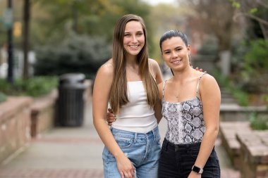 İki genç kadın yerel bir parkta birlikte gülüyor, ılık bahar havasının tadını çıkarıyorlar. Yeşillik ve günışığıyla çevrelenmiş, dostluk ve barış dolu neşeli ve tasasız bir anı paylaşıyorlar..