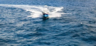 Parlak bir motorlu tekne okyanusu hızla geçerek dalgaları elektrikle kesiyor. Beyaz sprey ve köpüklü iz açık denizde yüksek hızlı maceranın heyecanını ve enerjisini yakalıyor..