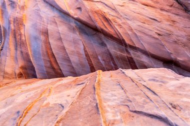 Nevada çölünden yükselen görkemli kaya oluşumları, güneşin altında parlayan engebeli dokuları, kurak arazinin ham güzelliğini vurgulayan engin mavi gökyüzüne karşı..
