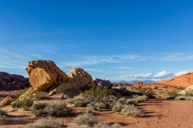 Nevada çölünden yükselen görkemli kaya oluşumları, güneşin altında parlayan engebeli dokuları, kurak arazinin ham güzelliğini vurgulayan engin mavi gökyüzüne karşı..